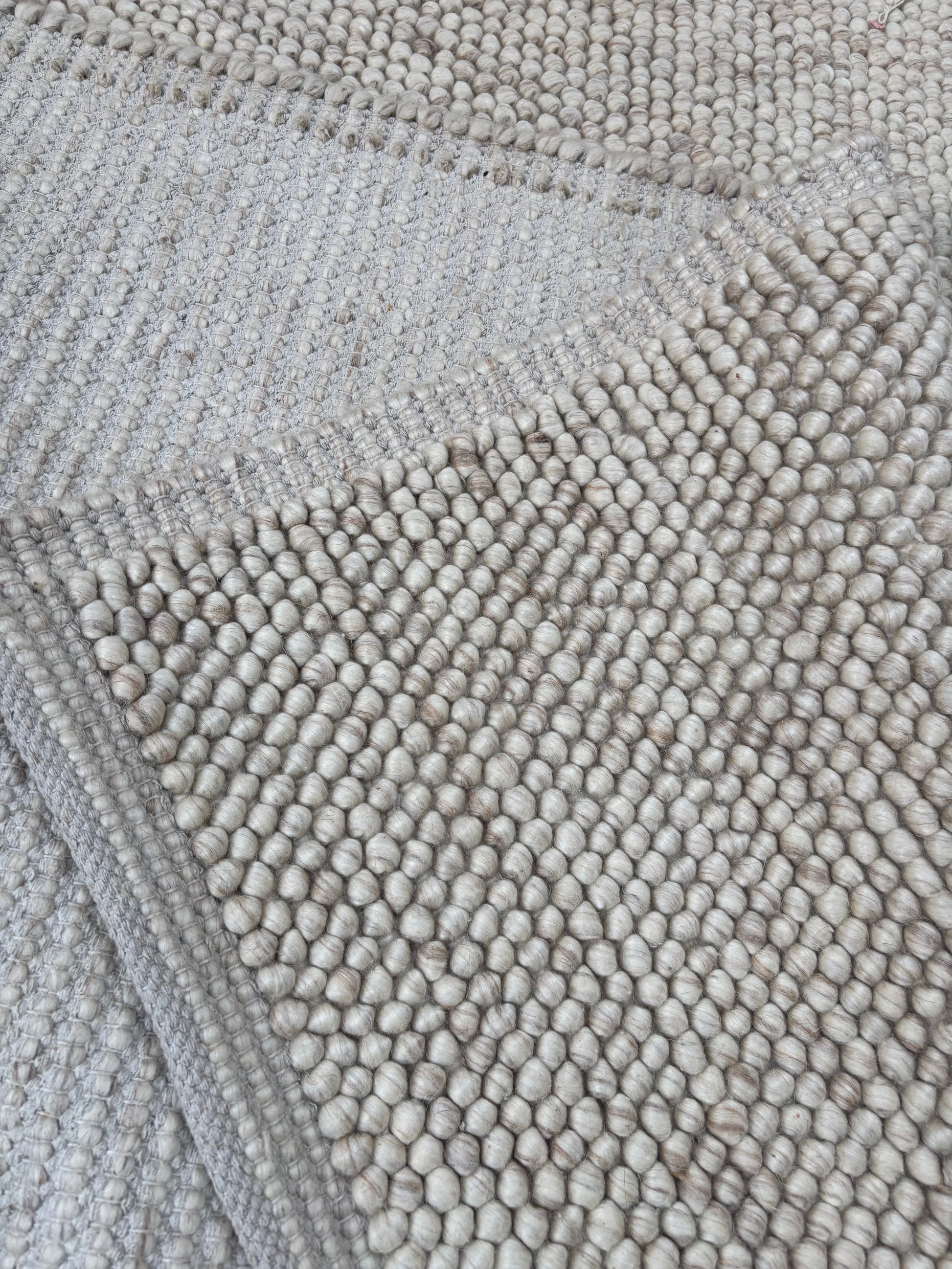 handwoven chunky loop wool rug corner detail beige cream bordered edge natural wool pile close up Lav and Lira