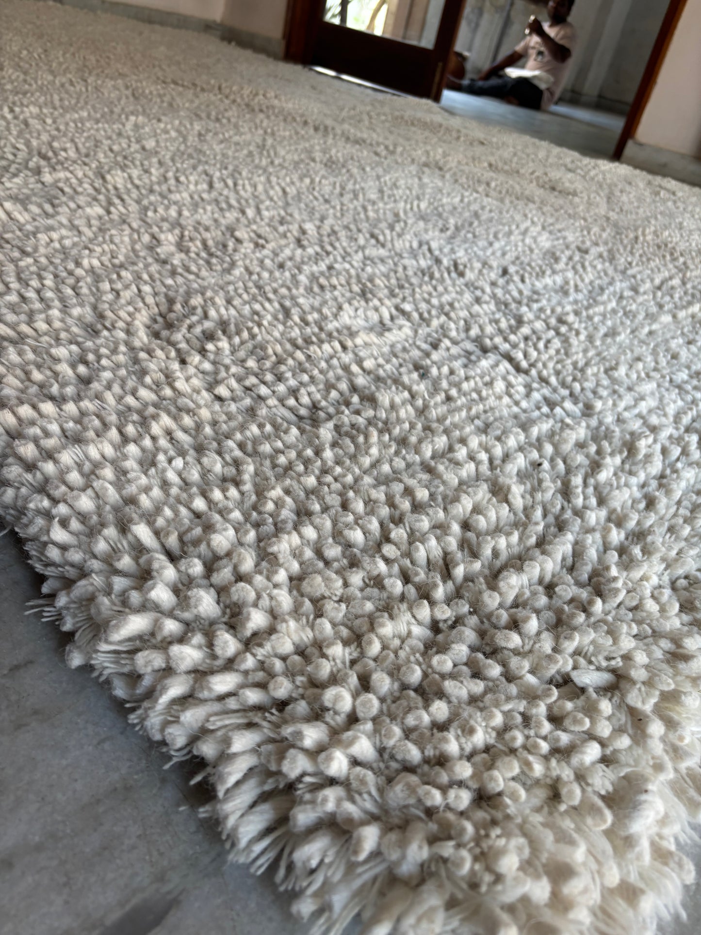 Close-up of handwoven white wool shaggy rug showing chunky knit pile texture and natural wool fibres