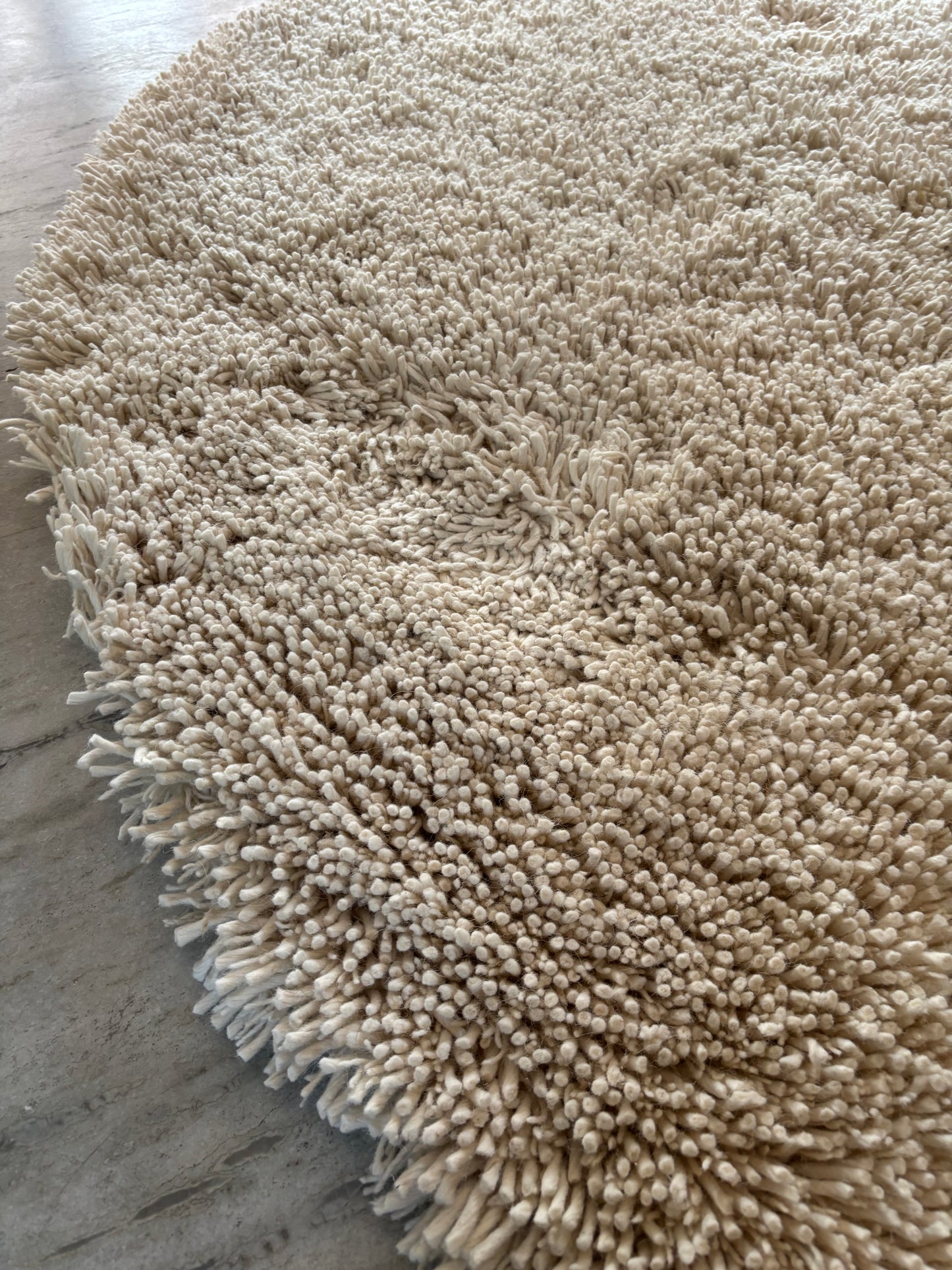 Edge detail of handwoven white shaggy wool rug showing thick plush pile height and natural wool construction