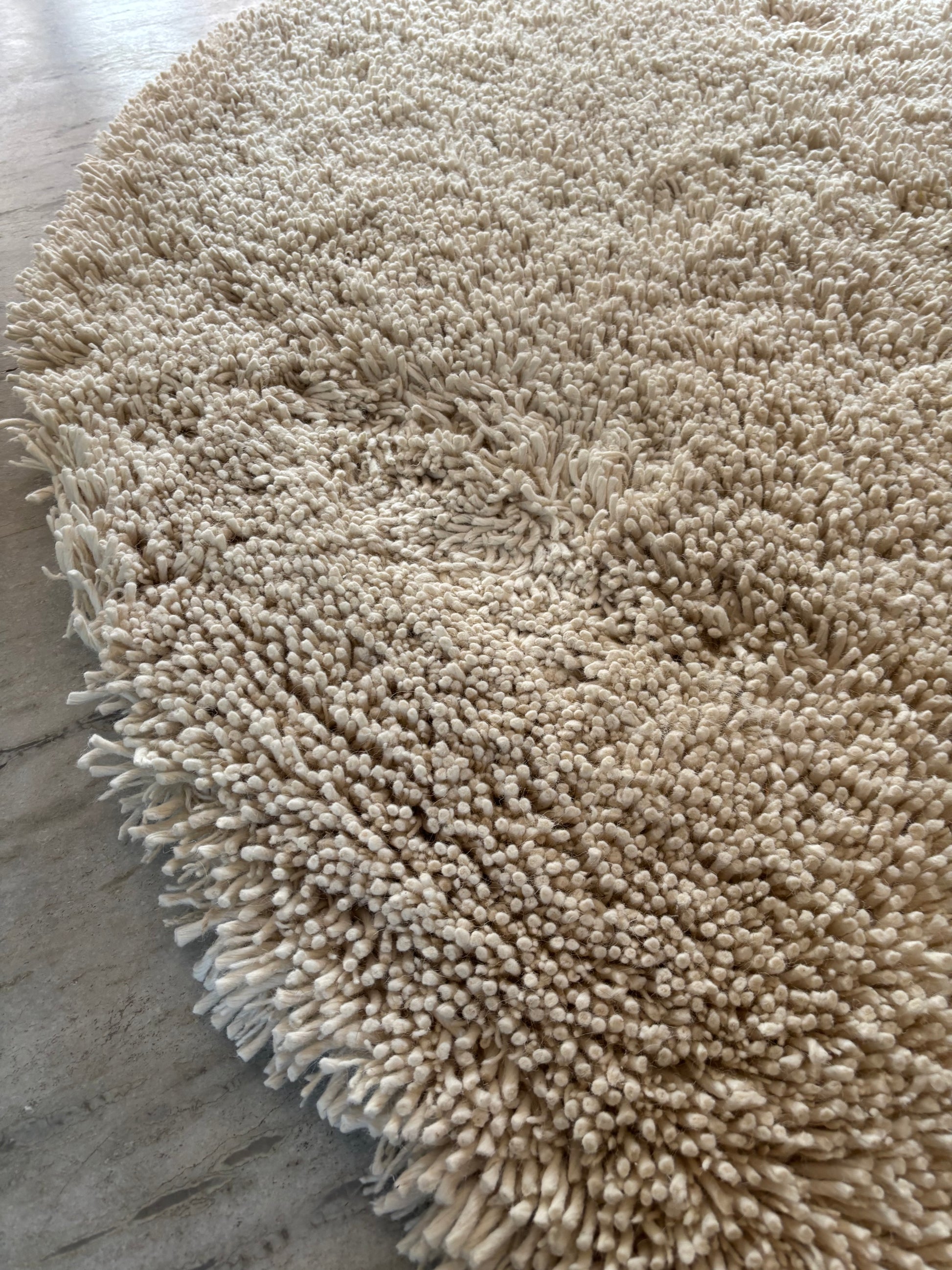 Edge detail of handwoven white shaggy wool rug showing thick plush pile height and natural wool construction