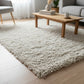 Handwoven white plush shaggy wool rug in a bright living room on hardwood floor, chunky knit texture by LavnLira