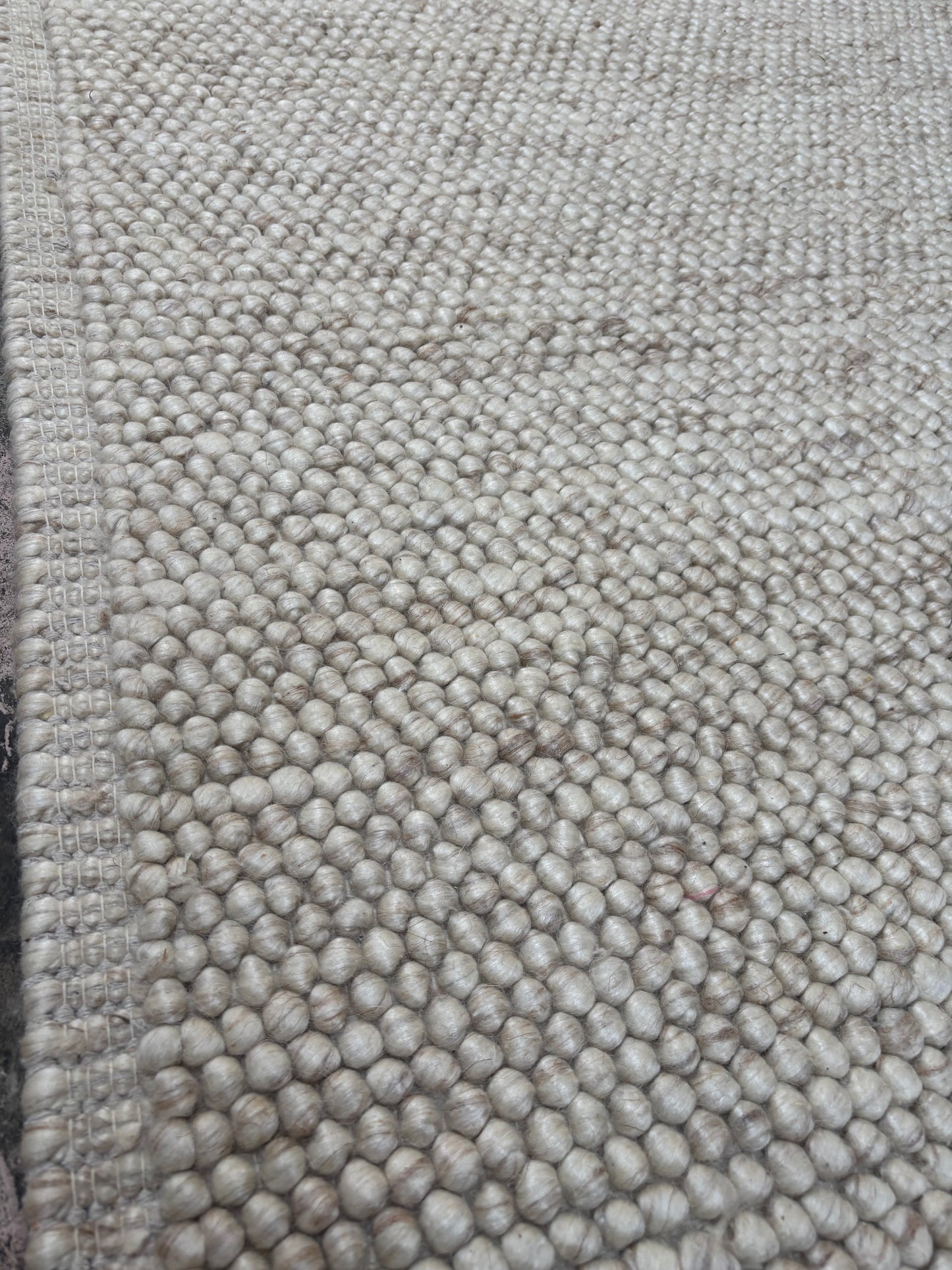 handwoven beige wool chunky loop rug beside bed bedroom interior neutral tones custom size Lav and Lira