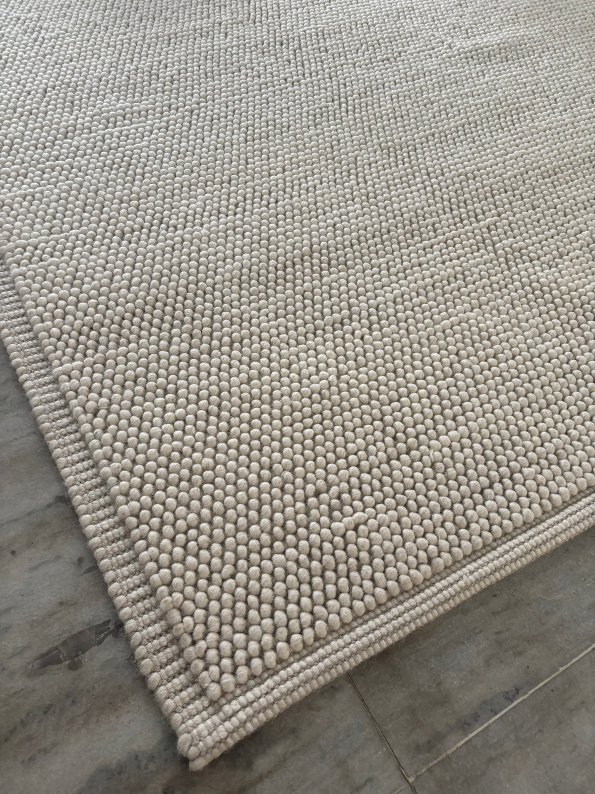 Close ups side angle ivory loop wool chunky rug with border